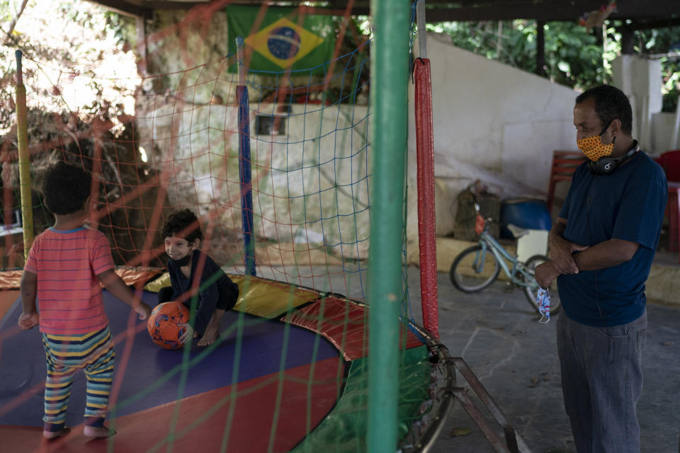 Marcio Antonio do Nascimento, the father of 25-year-old son Hugo do Nascimento who died from the new coronavirus, watches Hugo's sons, his grandchildren, play in Rio de Janeiro, Brazil, Saturday, Aug. 1, 2020. Brazil was leaping toward a grim milestone, 100,000 deaths from COVID-19, on Saturday, Aug. 8, and five months after the first reported case, the country had not shown signs of crushing the disease. (AP Photo/Leo Correa)