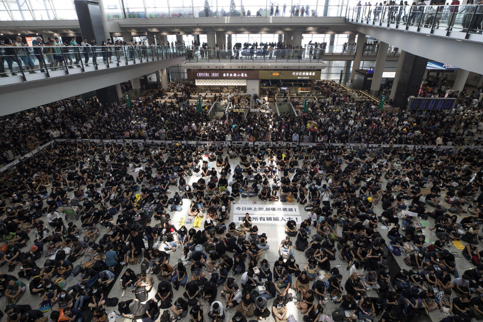 FILE - In this Aug. 12, 2019, file photo, protesters surround banners that read: "Those on the street today are all warriors!" center top, and "Release all the detainees!" during a sit-in rally at the arrival hall of the Hong Kong International airport in Hong Kong. Peaceful marches against proposed changes to the city’s extradition law morphed into nights of tear gas and rubber bullets. Hong Kong's protest movement has reached a moment of reckoning after protesters occupying the airport held two mainland Chinese men captive, and pro-democracy lawmakers and fellow demonstrators question whether the whole operation has gone too far. (AP Photo/Vincent Thian, File)