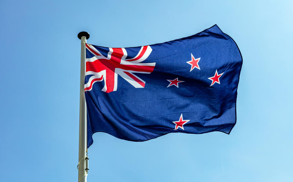 New Zealand flag, New Zealand national symbol waving against clear blue sky, sunny day