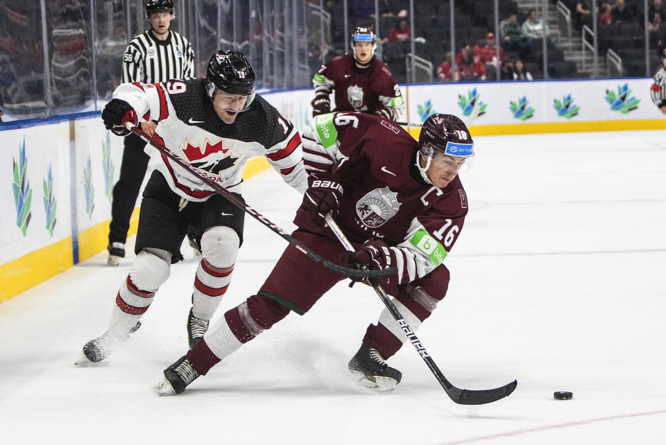 Canada's Elliot Desnoyers (19) and Latvia's Ralfs Bergmanis (16) battle for the puck during the second period of an IIHF junior world hockey championships game Wednesday, Aug. 10, 2022, in Edmonton, Alberta. (Jason Franson/The Canadian Press)