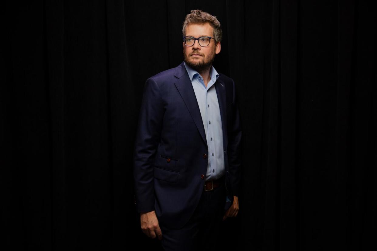 A man stands against a black background.