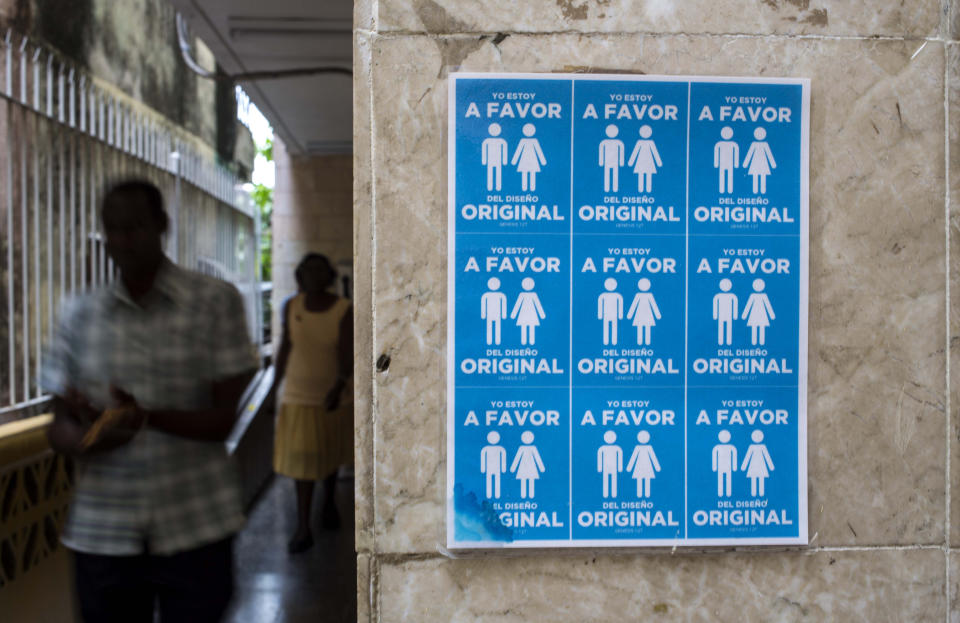 En esta imagen, tomada el 7 de octubre de 2018, un cartel con símbolos de parejas heterosexuales colocado en el exterior de una iglesia de la Liga Evangélica con el lema "Yo estoy a favor del diseño original", contra la legalización de los matrimonios homosexuales antes de una reforma constitucional, en La Habana, Cuba. La enmienda más polémica es una que permitiría que gays y lesbianas se casen. (AP Foto/Desmond Boylan)