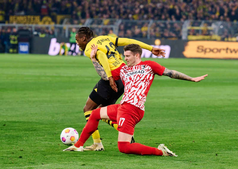 Borussia Dortmund's Jamie Bynoe-Gittens and Freiburg's Lukas Kuebler battle for the ball during the German Bundesliga soccer match between Borussia Dortmund and SC Freiburg at the Signal Iduna Park. Bernd Thissen/dpa