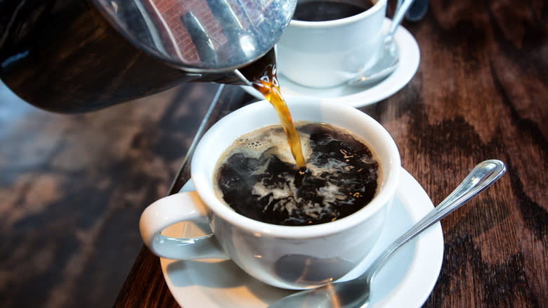 A cup of coffee being poured into a mug