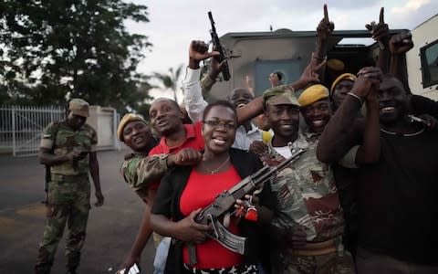 People and soldiers celebrate after the resignation of Zimbabwe's president on November 21, in Harare - Credit:  MARCO LONGARI/AFP