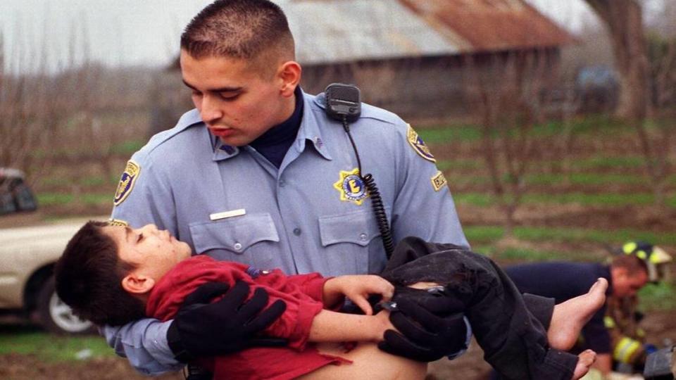 El Explorador de Carreteras de California Mayolo Bañuelos lleva a un niño herido a una ambulancia que le espera en el lugar de un accidente ocurrido en 1999 al oeste de Modesto. Bañuelos hizo carrera como agente de la CHP y ahora es comandante de la oficina de la zona de Modesto.