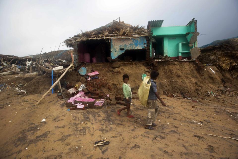 Boys walk past damaged houses belonging to fishermen after Cyclone Phailin hit Puri