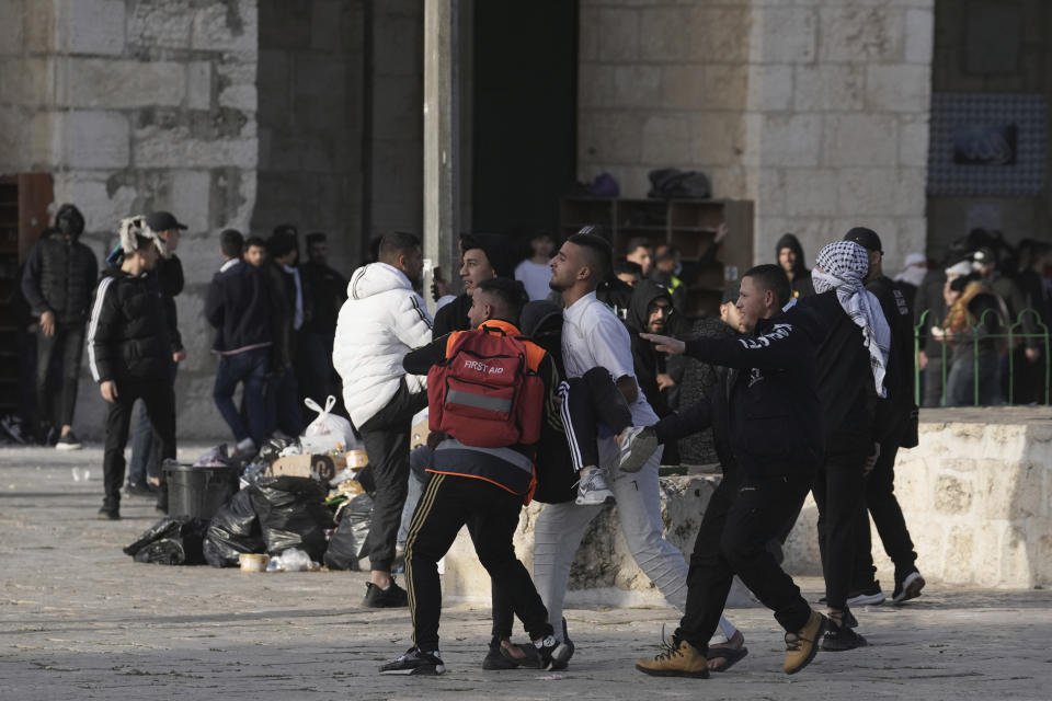 A Palestinian protester wounded in clashes with Israeli police is carried to safety at the Al Aqsa Mosque compound in Jerusalem's Old City, Friday, April 22, 2022. Israeli police and Palestinian youths clashed again at the major Jerusalem holy site sacred to Jews and Muslims on Friday despite a temporary halt to Jewish visits to the site, which are seen as a provocation by the Palestinians. (AP Photo/Mahmoud Illean)