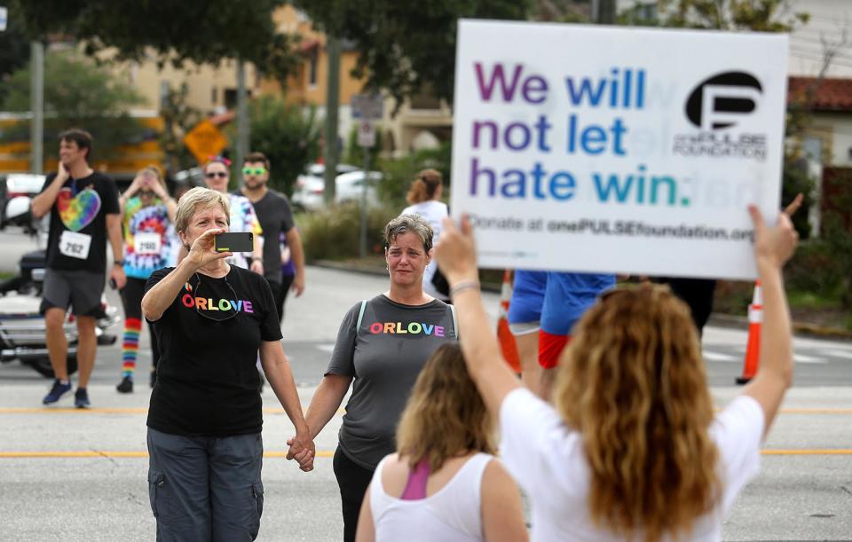 <p>Pulse nightclub owner Barbara Poma holds up a sign for runners passing her club during the CommUNITYRainbowRun 4.9K road race on Saturday, June 10, 2017, in Orlando, Fla. (Joe Burbank/Orlando Sentinel/TNS via Getty Images) </p>