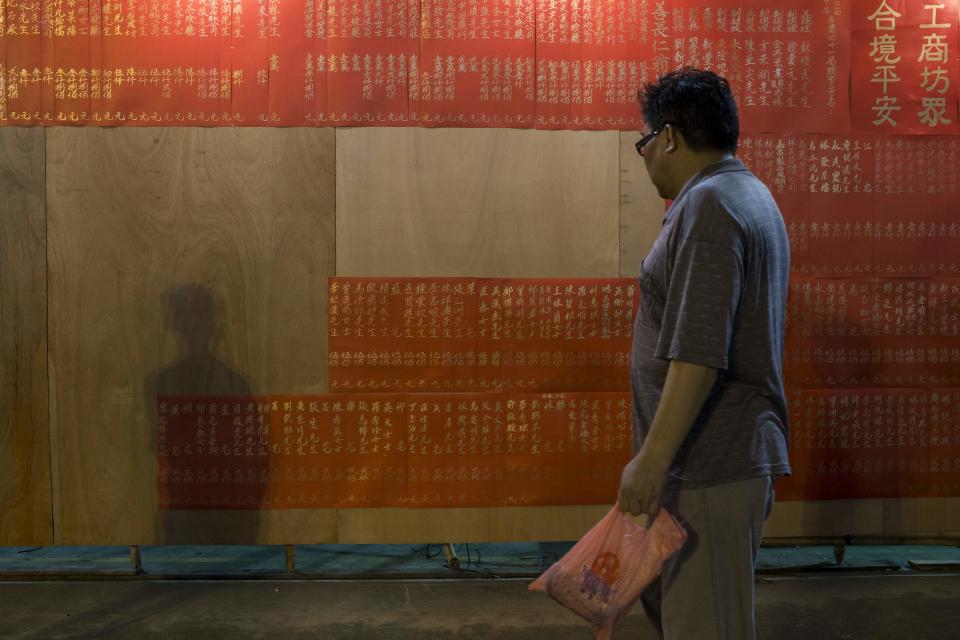 A man looks at a list of donors for a Chinese Hungry Ghost Festival ceremony in Hong Kong August 8, 2014. The Ghost Festival, also known as Yu Lan, is a traditional Chinese festival on the 15th night of the seventh month of the Chinese calendar. In Chinese tradition, the month is regarded as the Ghost Month, in which ghosts and spirits, including those of deceased ancestors, come out from the lower realm to visit the living. Worshippers prepare ritualistic food offerings and burn joss paper - a paper form of material items - for the ghost. Other paper items in the form of clothes, gold and other fine goods are also burnt for the visiting spirits of the ancestors to show respect.REUTERS/Tyrone Siu (CHINA - Tags: RELIGION SOCIETY)