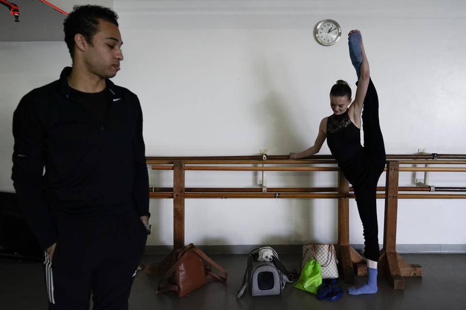 Adrian Blake Mitchell, left, and Andrea Laššáková warm up near their dog, Beau, before rehearsing on Monday, April 18, 2022, in Santa Monica, Calif. The dancers left their positions at the Mikhailovsky Ballet Theatre in St. Petersburg and fled Russia ahead of the invasion of Ukraine. (AP Photo/Ashley Landis)