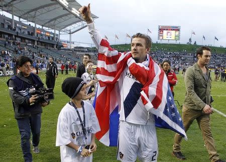 Los Angeles Galaxy's David Beckham gives a thumbs up to the crowd next to his son Romeo after Galaxy defeated the Houston Dynamo to win the MLS Cup championship soccer game in Carson, California, December 1, 2012. REUTERS/Danny Moloshok