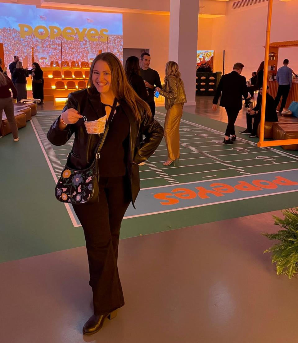 The writer at the Popeyes taste test, holding a chicken wing