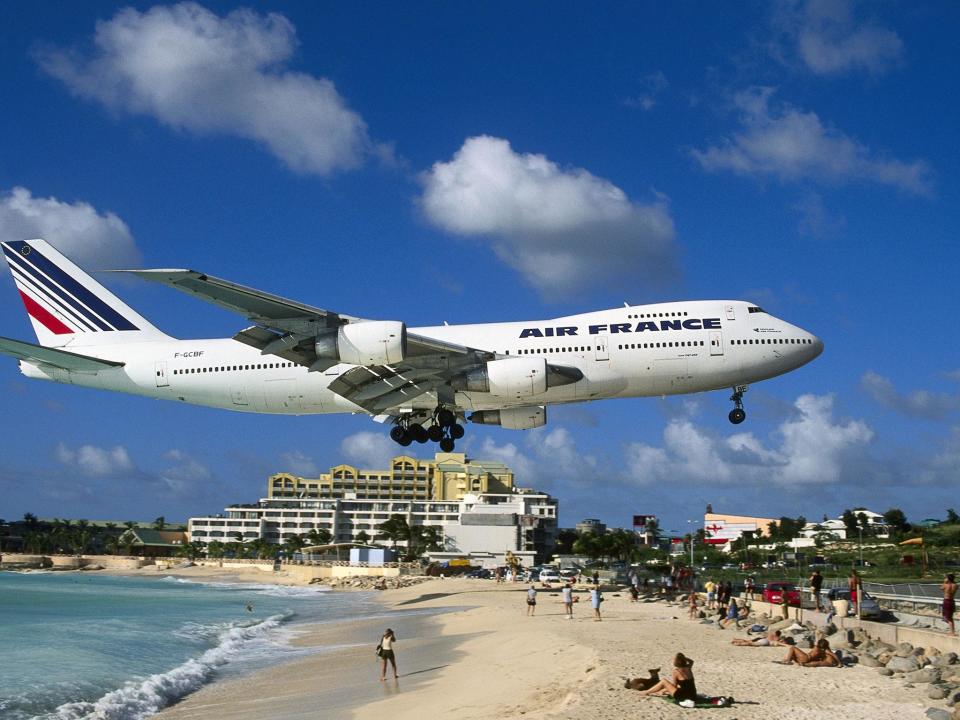 Princess Juliana International Airport is famed for planes flying over beach-goers' heads as plane spotters cling to fences to feel the jet blast of aircraft taking off: Rex Features