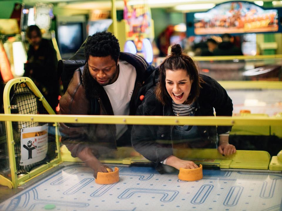 A man and a woman play at an arcade.