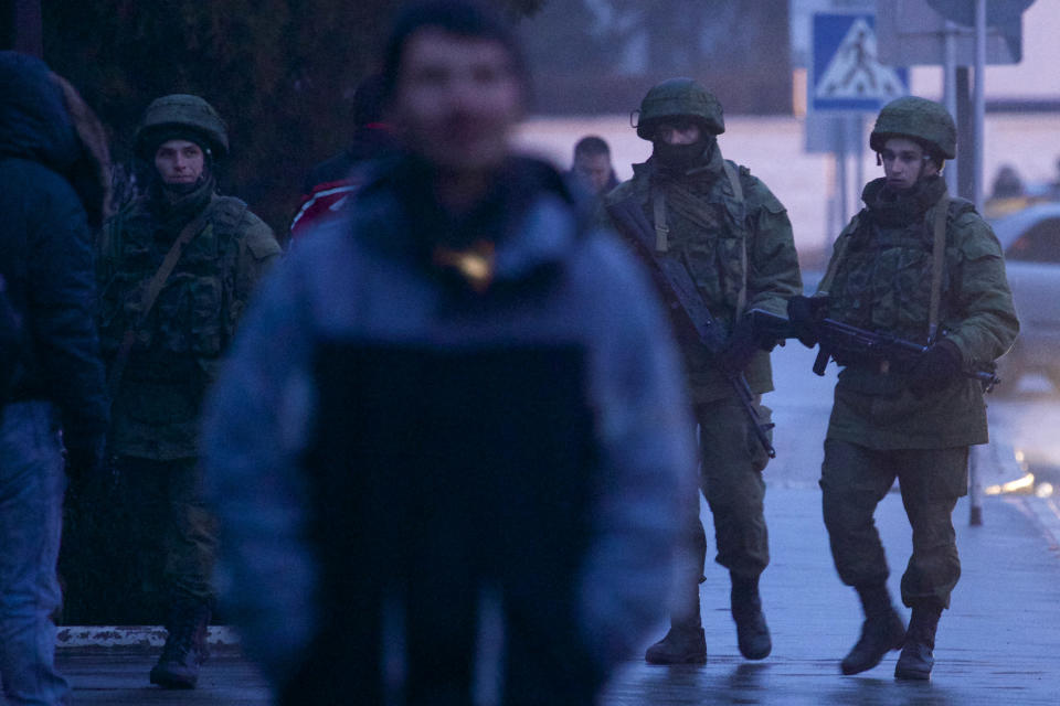 Unidentified armed men patrol a square in front of the airport in Simferopol, Ukraine, Friday, Feb. 28, 2014. Dozens of armed men in military uniforms without markings occupied the airport in the capital of Ukraine's strategic Crimea region.(AP Photo/Ivan Sekretarev)