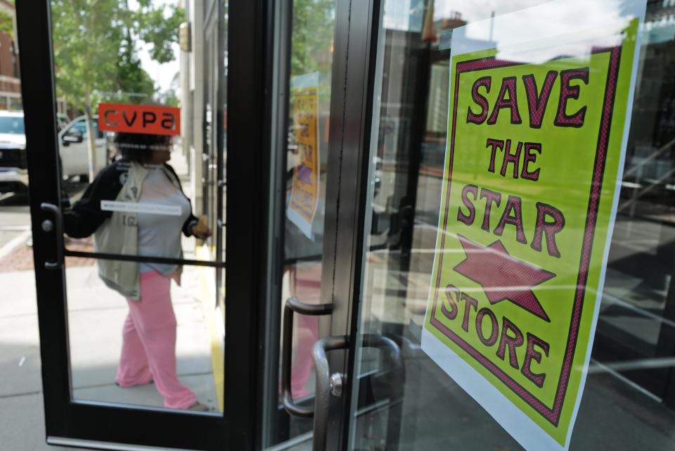 A woman walks into the UMass Dartmouth Star Store campus in downtown New Bedford past a sign to Save the Star Store.