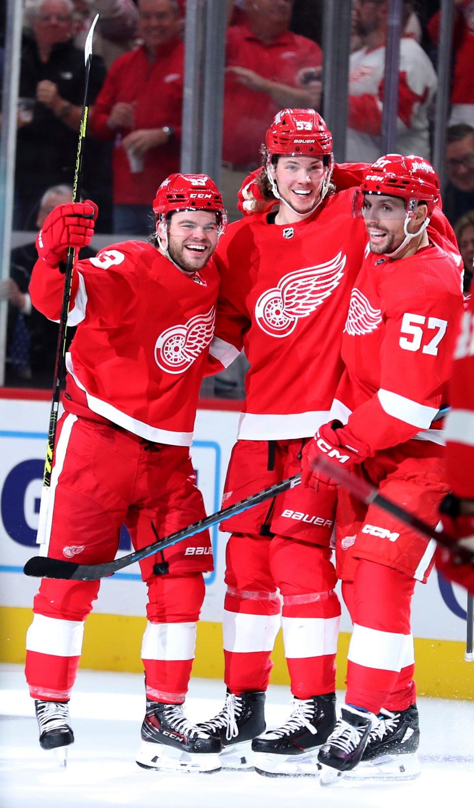 Red Wings right wing Alex DeBrincat, left, celebrates with defenseman Moritz Seider, center, and left wing David Perron after he scored against Seattle during the third period of the Wings' 5-4 overtime loss on Tuesday, Oct. 24, 2023, at Little Caesars Arena.