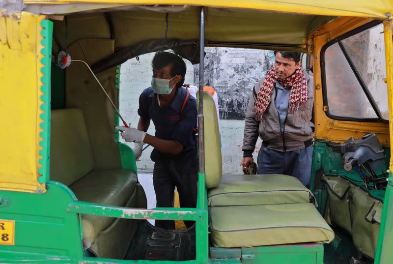 A worker disinfects an autorickshaw as part of a preventive measure against coronavirus, in New Delhi