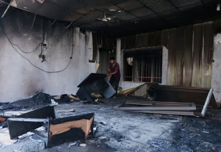 Man is seen at the headquarters of the Islamic Dawa Party which was burnt by the demonstrators during a curfew, two days after the nationwide anti-government protests turned violent, in Najaf