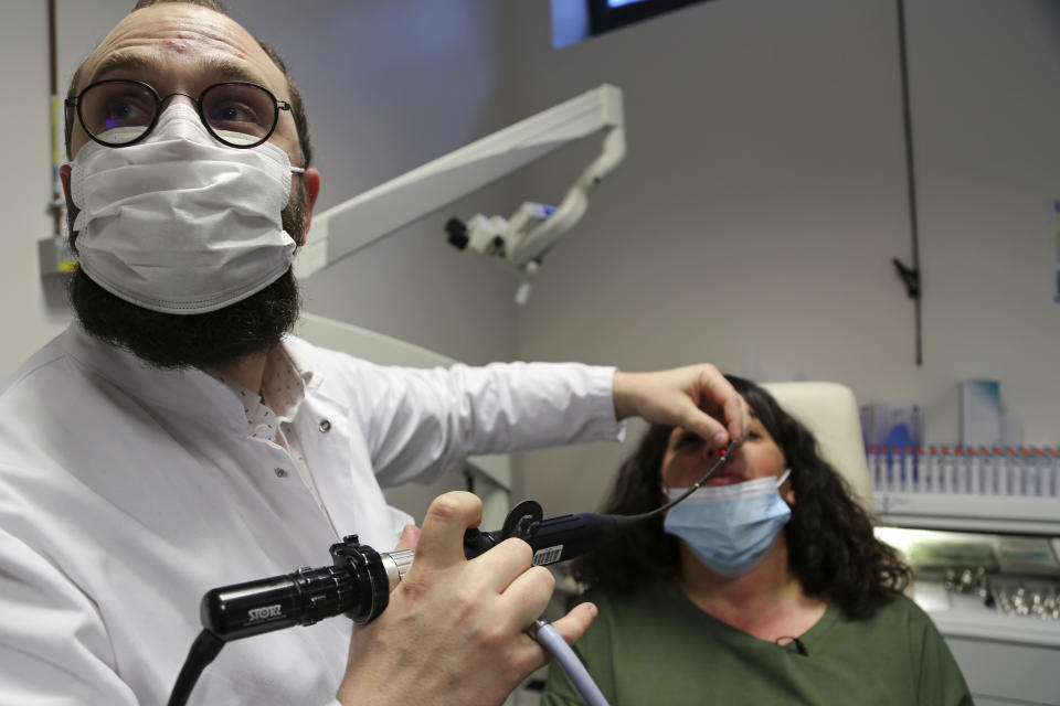 Dr. Clair Vandersteen, left, uses a miniature camera at his hospital in Nice, France, on Monday, Feb. 8, 2021, to check inside the nasal passages of a patient, Gabriella Forgione, who says she has been unable to smell or taste since she contracted COVID-19 in November 2020. A year into the coronavirus pandemic, doctors and researchers are still striving to better understand and treat the accompanying epidemic of COVID-19-related anosmia — loss of smell — draining much of the joy of life from an increasing number of sensorially frustrated longer-term sufferers like Forgione. (AP Photo/John Leicester)