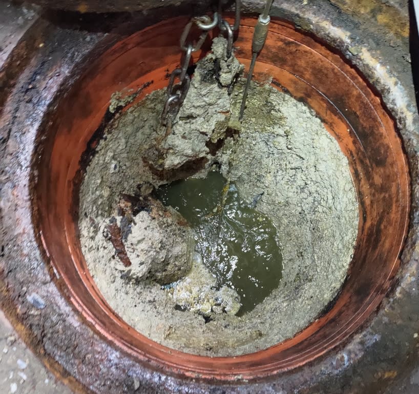《圖說》污水下水道人孔內部沉積油塊皂化清疏中。〈水利局提供〉