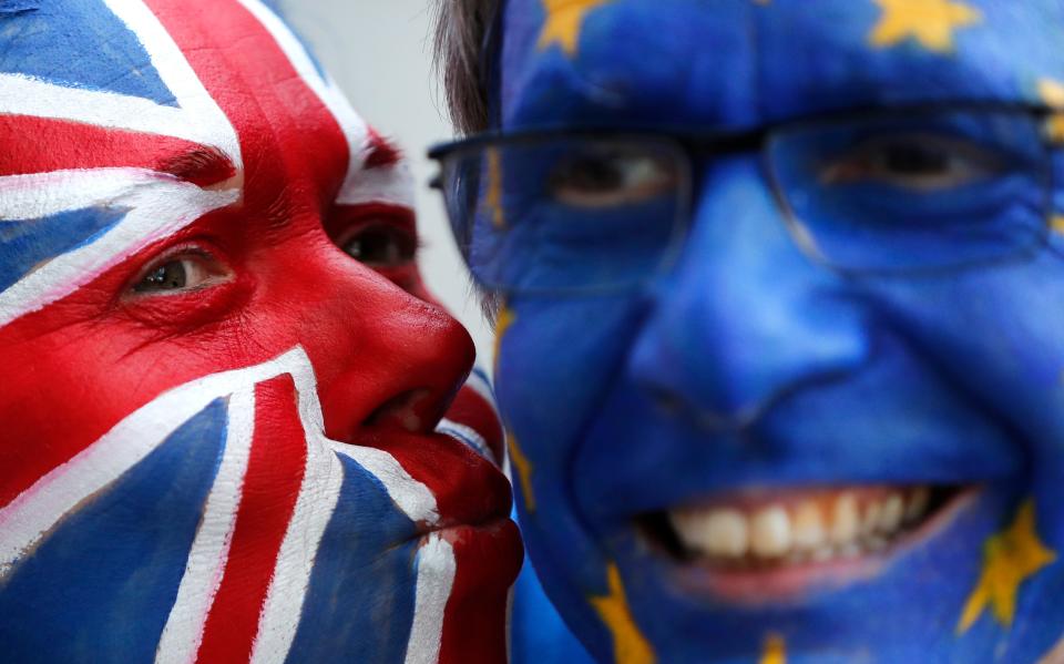 Activists pose with their faces painted in the British and EU colors during an anti-Brexit campaign stunt outside EU headquarters in Brussels, Belgium, on March 21, 2019.