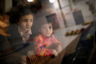 Syrian refugee children from the Abdulwahed family look out to the curling rink as it is reflected in the glass at the Royal Canadian Curling Club, during an event where refugees were introduced to the sport of curling put on by the "Together Project", in Toronto, March 15, 2017. REUTERS/Mark Blinch