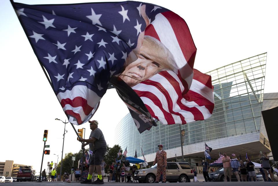 Trump supporter Randall Thom waves a giant Trump flag to passing cars outside the BOK Center June 18, 2020 in Tulsa, Oklahoma. Trump is scheduled to hold his first political rally since the start of the coronavirus pandemic at the BOK Center on Saturday while infection rates in the state of Oklahoma continue to rise.