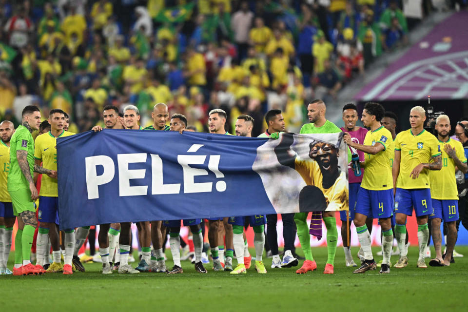 Brazil players stand behind a banner honouring Brazilian football legend Pele after they won the Qatar 2022 World Cup round of 16 football match between Brazil and South Korea at Stadium 974 in Doha on December 5, 2022. (Photo by MANAN VATSYAYANA / AFP)