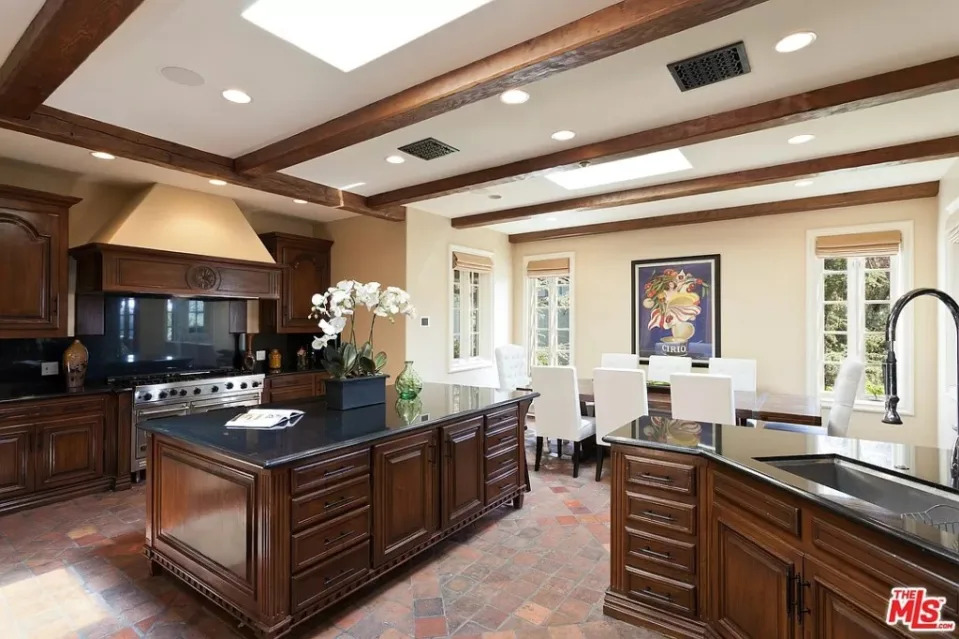 The kitchen boasts an expansive island and a dining area with skylights. MLS