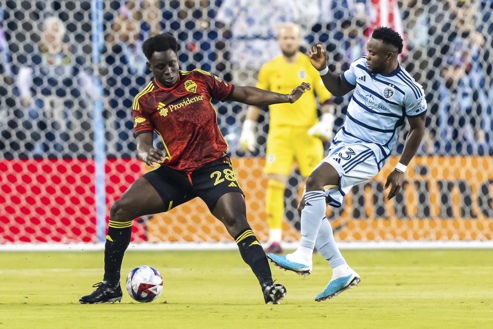 El zaguero Yeimar Gómez (izquierda) de los Sounders de Seattle domina el balón ante el delantero Willy Agada del Sporting Kansas City, el sábado 25 de marzo de 2023, en Kansas City, Kansas. (AP Foto/Nick Tre. Smith)