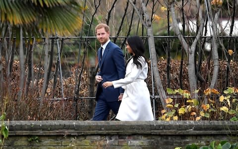 Prince Harry and Meghan Markle walk through the grounds of Kensington Palace - Credit: TOBY MELVILLE/Reuters