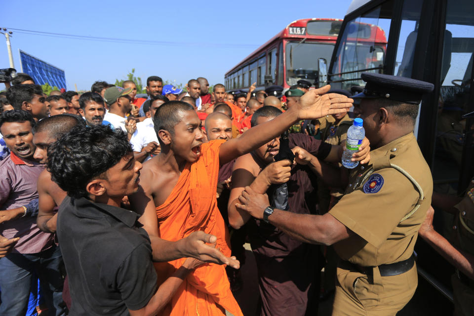 FILE - In this Jan. 7, 2017, file photo, a Sri Lankan Buddhist monk and villagers argue with police officers during a protest outside the inauguration ceremony of an industrial zone in which China had a major stake in Mirijjawila village in Ambalantota, Sri Lanka. China's loans to poor countries in Africa and Asia impose unusual secrecy and repayment terms that are hurting their ability to renegotiate debts after the coronavirus pandemic, a group of U.S. and German researchers said in a report Wednesday, March 31, 2021. (AP Photo/Eranga Jayawardena, File)