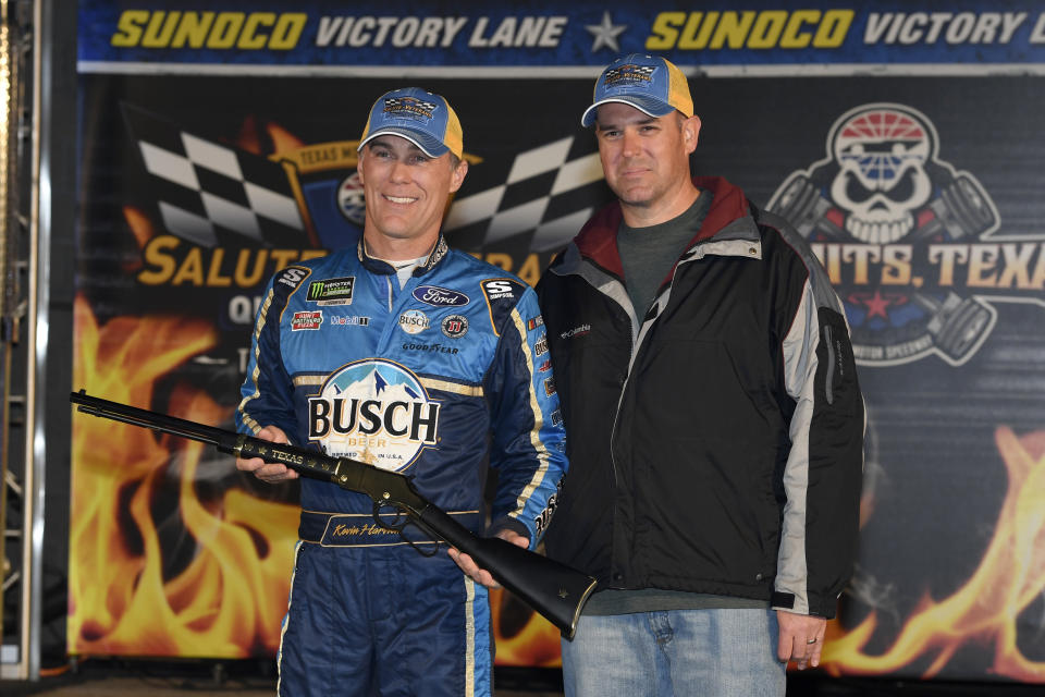 Kevin Harvick, left, poses with local military veteran Joshua Hoscheid, right, in Victory Lane after Harvick won the pole for Saturday's NASCAR Cup Series auto race at Texas Motor Speedway in Fort Worth, Texas, Saturday, Nov. 2, 2019. (AP Photo/Larry Papke)