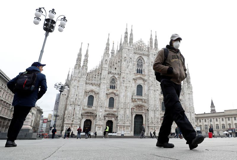 A man wearing a face mask walks past Piazza Duomo square in Milan