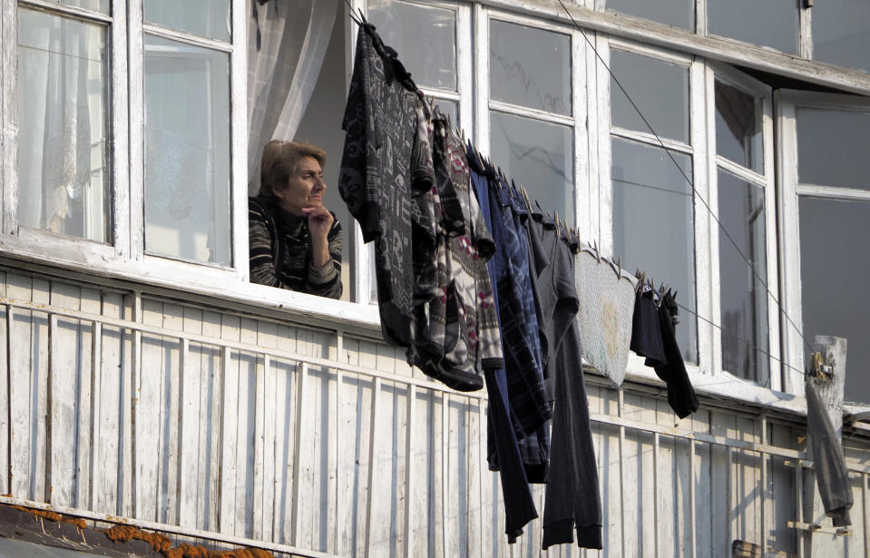 A woman looks through the window of her apartment in Stepanakert, the separatist region of Nagorno-Karabakh, Tuesday, Nov. 3, 2020. Fighting over the separatist territory of Nagorno-Karabakh entered sixth week on Sunday, with Armenian and Azerbaijani forces blaming each other for new attacks. (AP Photo)