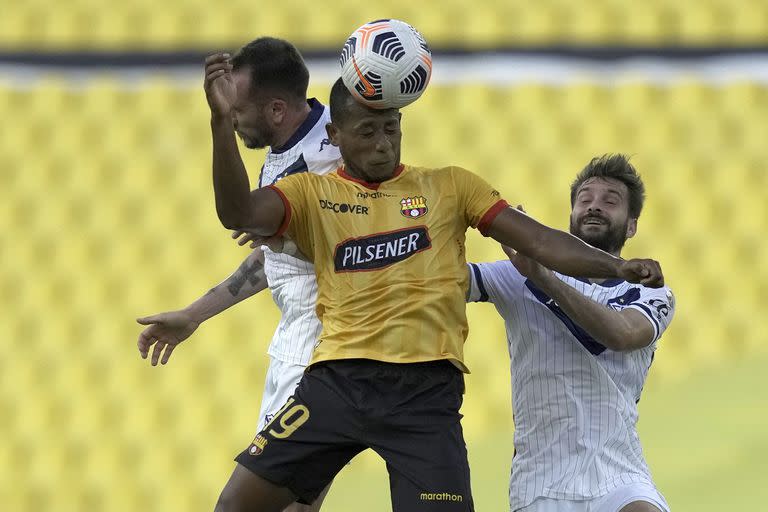 El ecuatoriano Luis Fernando León (C) pelea por el balón con Federico Mancuello y Agustín Bouzat