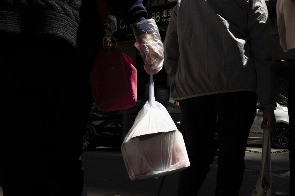 A pedestrian carries takeaway food plastic bag in Hong Kong, Wednesday, March 13, 2024. Hong Kong has long been a major producer and consumer of great food, and a great amount of plastic and Styrofoam to go with it. That’s going to change as new legislation aiming to stop the sale and distribution of Styrofoam products and single-use plastic cutlery went into effect on Monday, April 22, 2024. (AP Photo/Louise Delmotte)