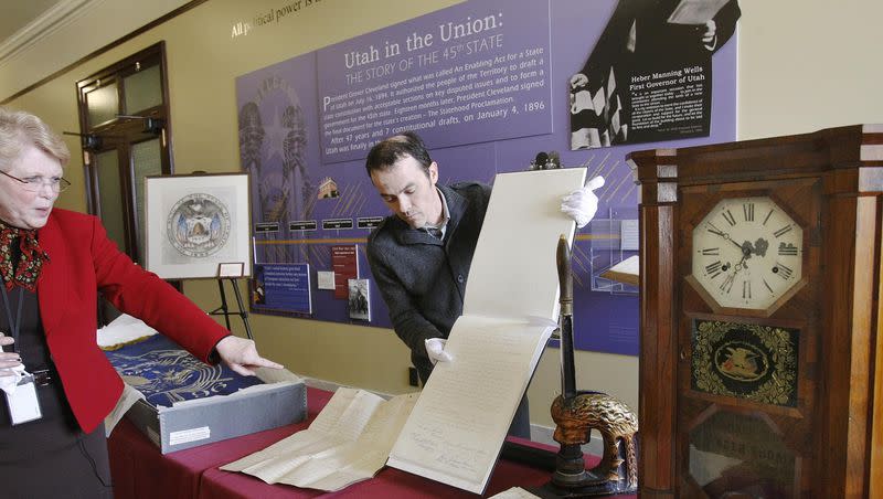 Judith McConkie, curator of the Utah State Capitol, points out the original Utah state Constitution being held by Ken Williams of the Utah State Archives and Records Service March 8, 2010. The clock on the end of the table was gift from John Bernhisel to President Brigham Young.