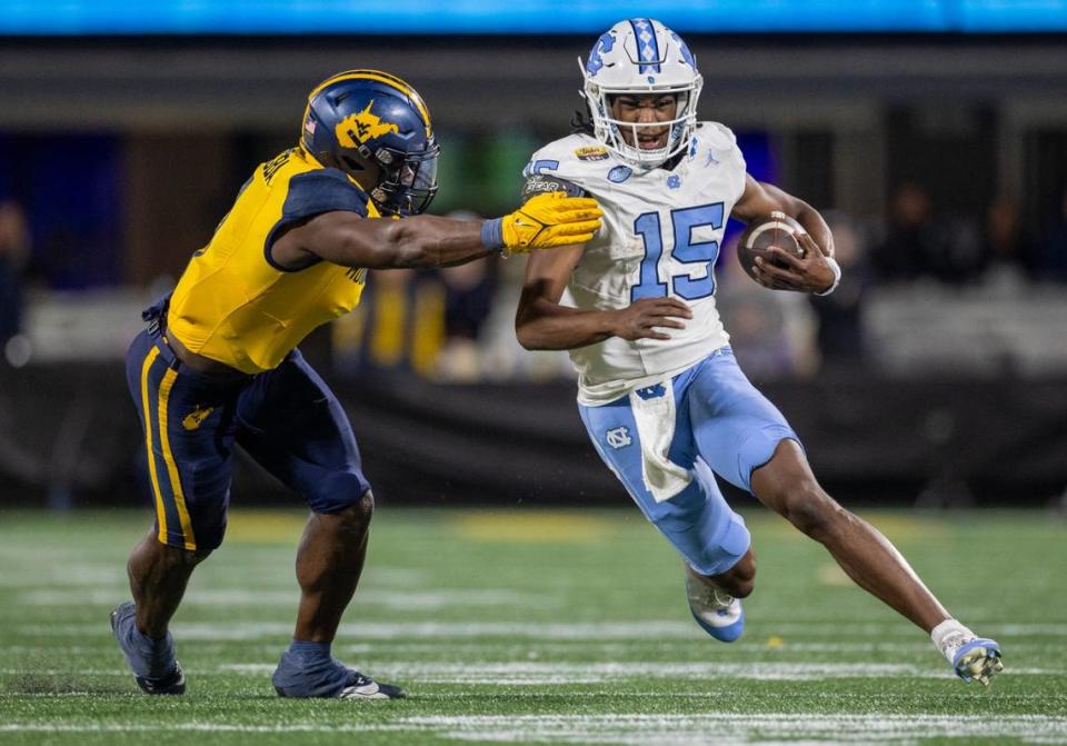 North Carolina quarterback Conner Harrell (15) looks for running room on a 11-yard carry in the second quarter against West Virginia’s Lee Kpogba (1) on Wednesday, December 27, 2023 at Bank of American Stadium in Charlotte, N.C. Robert Willett/rwillett@newsobserver.com