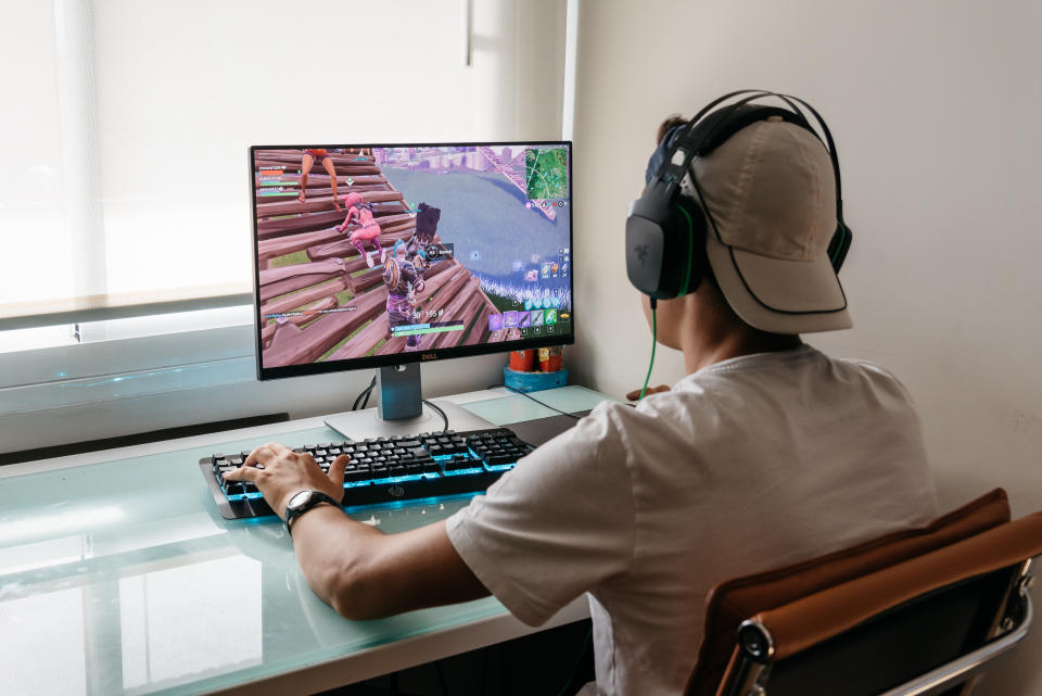 Teenager plays Fortnite on a desktop computer while wearing headphones