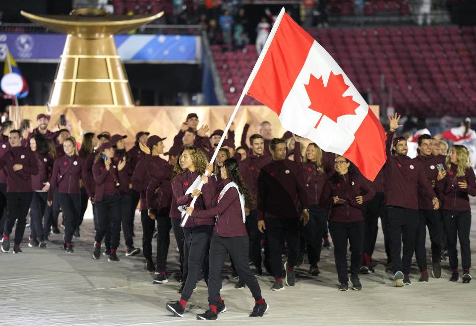 Canada's Brandie Wilkerson and Melissa Humana-Paredes carry their country's flag as they lead other Canadian athletes into the stadium during the opening ceremony of the Pan American Games in Santiago, Chile, Friday, Oct. 20, 2023. (Frank Gunn/The Canadian Press via AP)