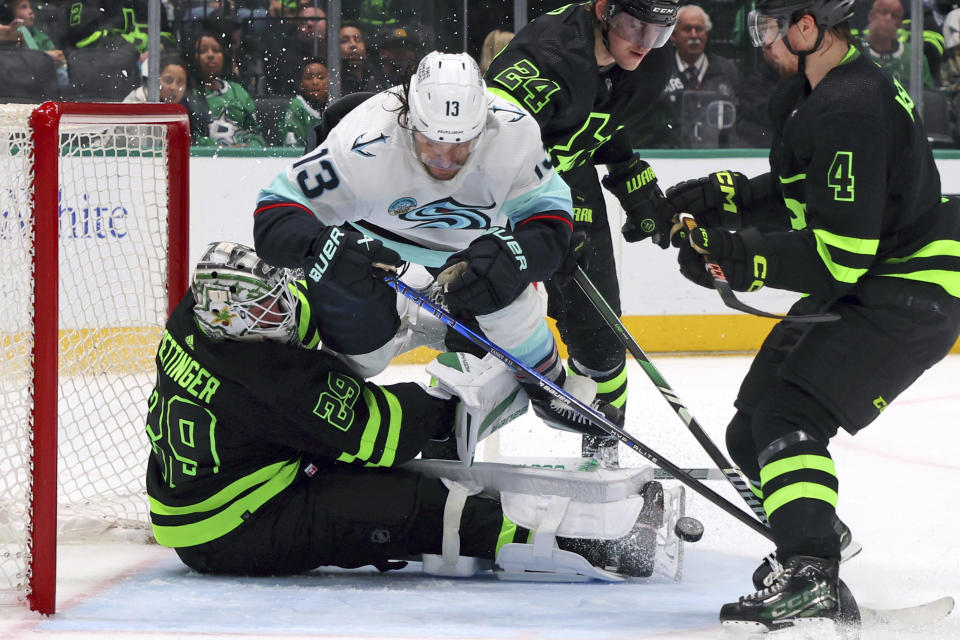 Dallas Stars goaltender Jake Oettinger (29) gets slammed into by Seattle Kraken left wing Brandon Tanev (13) as he shoots in the second period of an NHL hockey game on Saturday, April 13, 2024, in Dallas. (AP Photo/Richard W. Rodriguez)