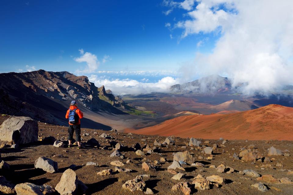 Tourist hiking in Haleakala volcano crater on the Sliding Sands trail. Beautiful view of the crater floor and the cinder cones below. Maui, Hawaii, USA.