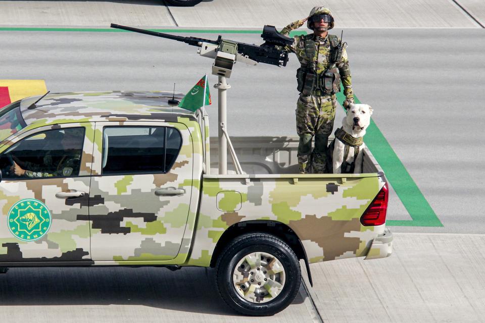 A Turkmenistan army soldier with a shepherd dog Alabay rides a pickup during a military parade celebrating the country's 30th independence anniversary in Ashgabat, Turkmenistan, Monday, Sept. 27, 2021. The pomp-filled parade took place in Ashgabat, the capital of the gas-rich former Soviet nation in Central Asia. Aside from troops and military equipment, the parade featured employees of state ministries and institutions demonstrating their achievements and Alabai dogs, which accompanied soldiers on military vehicles. (AP Photo/Alexander Vershinin)