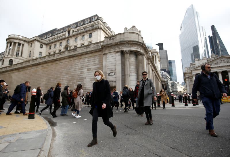 A woman wearing a protective face mask, following an outbreak of the coronavirus, walks in front of the Bank of England in London