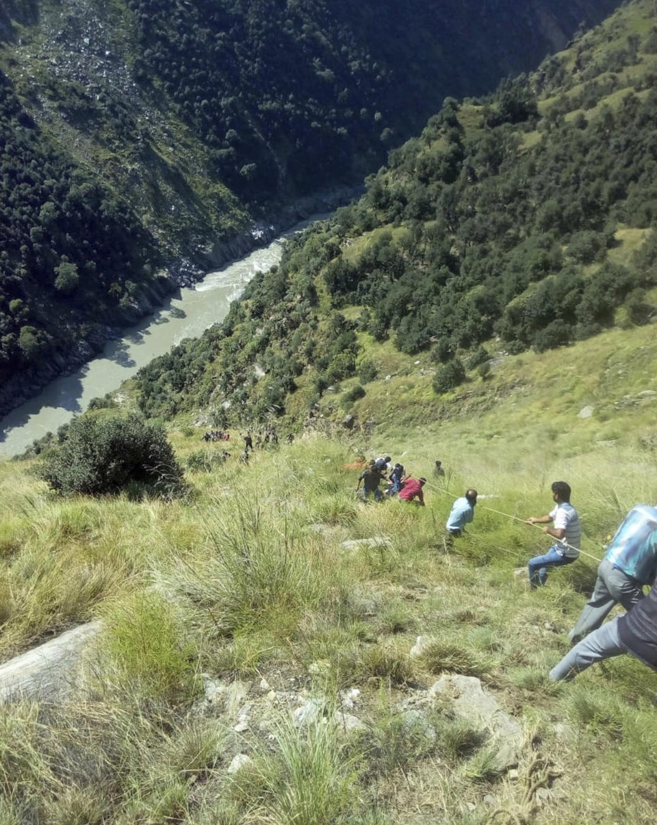 Rescuers try to reach a bus that fell into a gorge near Kishtwar, about 217 kilometers (135 miles) southeast of Srinagar, Indian-controlled portion of Kashmir, Friday, Sept. 14, 2018. The bus fell off a road into a deep gorge killing more than a dozen people. (AP Photo/Balbir Singh Jamwal)