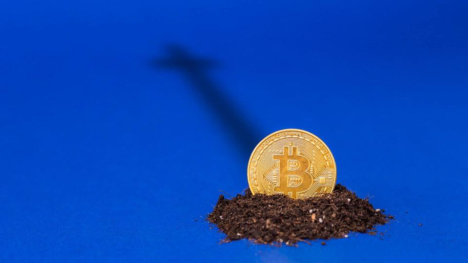 Moeda de bitcoin sobre a terra com sombra de uma cruz