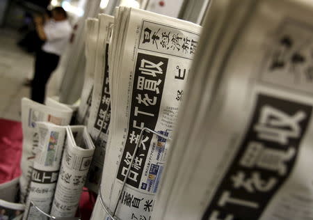 The front page of Japan's Nikkei newspapers reporting Japanese media group Nikkei's acquisition of the Financial Times from Britain's Pearson are seen in front of a man outside a store in Tokyo, Japan, July 24, 2015. REUTERS/Yuya Shino